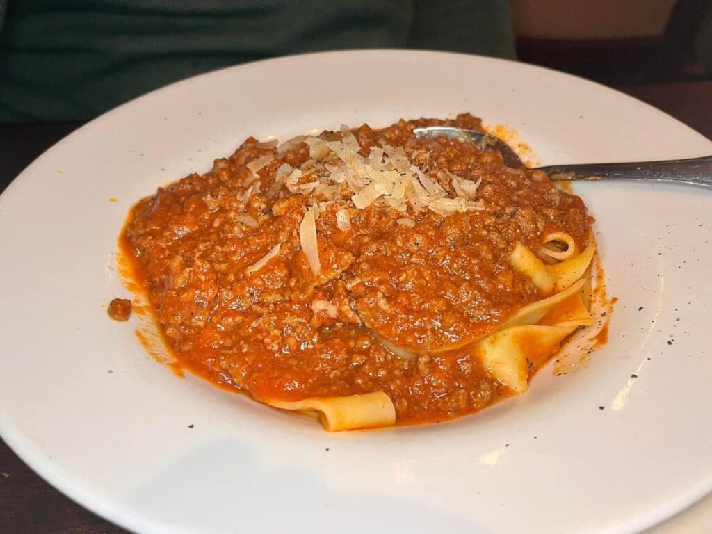 Pappardelle bolognese topped with shaved parmigiano