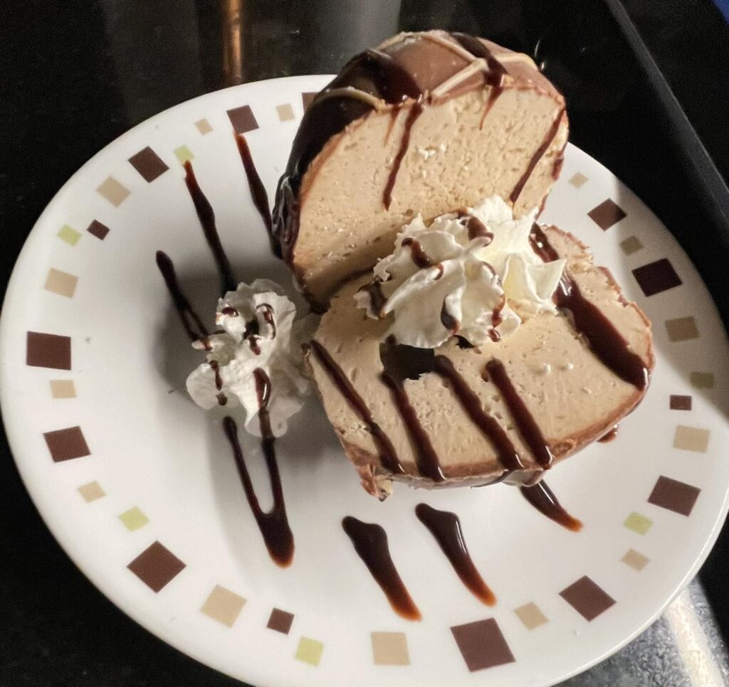 Sliced frozen bomba with chocolate drizzle and whipped cream