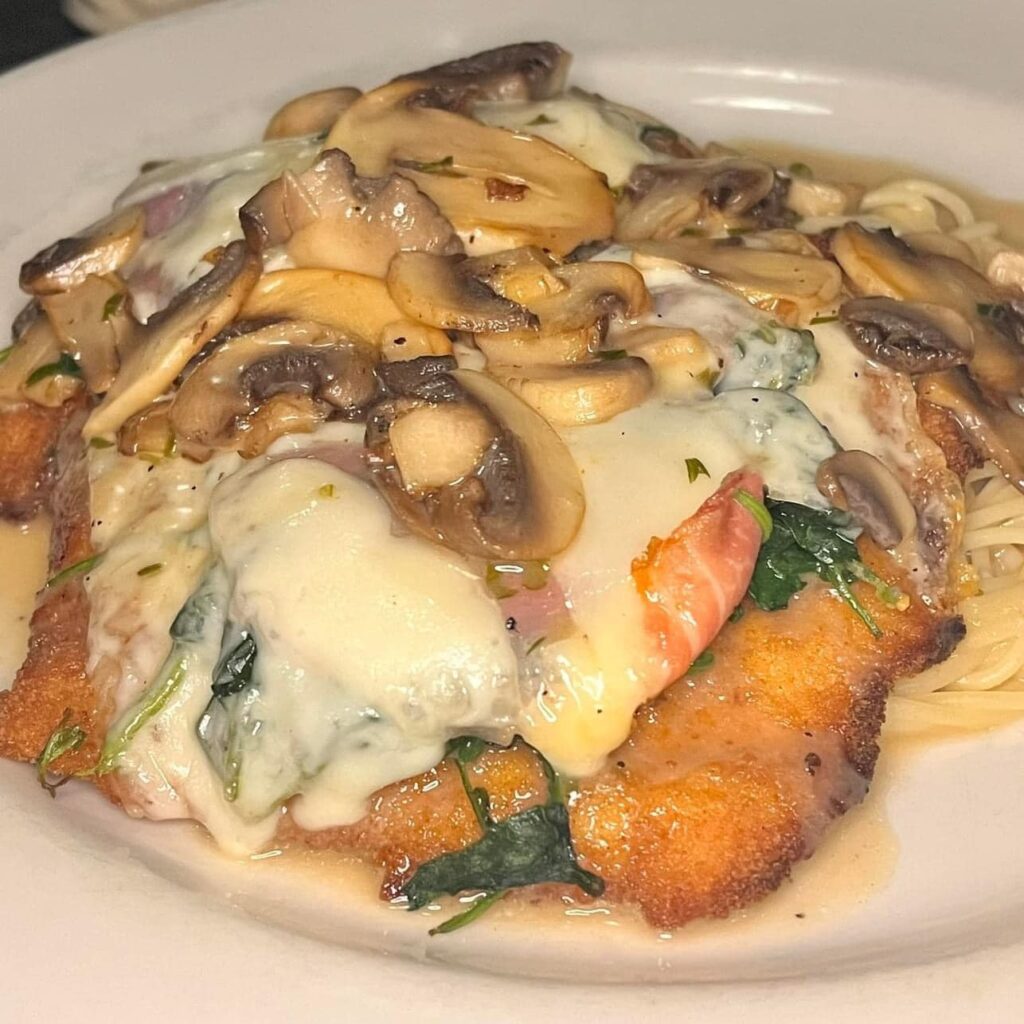 Chicken saltimbocca with prosciutto, spinach, mushrooms and melted cheese over linguine