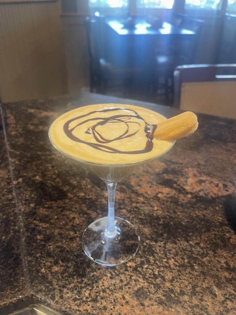 Tiramisu martini with chocolate drizzle and a ladyfinger