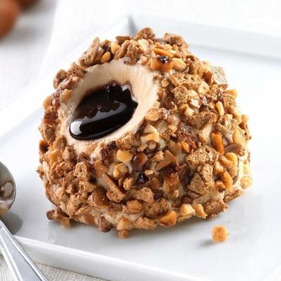 Peanut butter dream bomba coated in crushed nuts with caramel centre