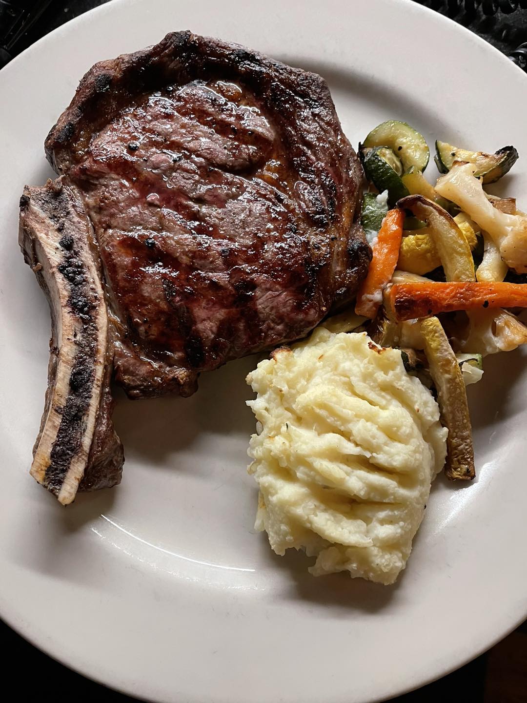 Grilled bone-in ribeye with whipped potatoes and roasted vegetables
