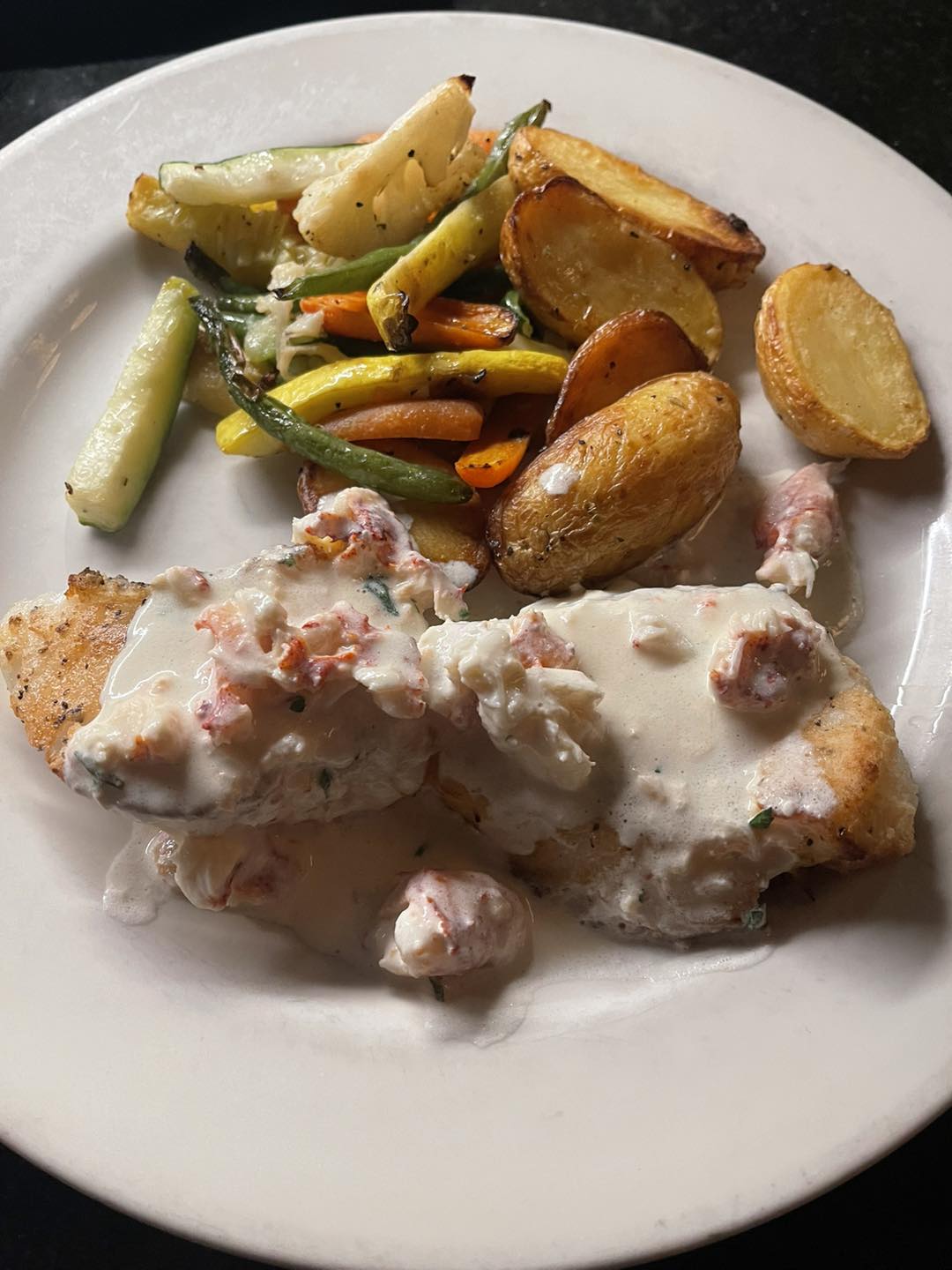 Baked haddock in lobster cream sauce with roasted potatoes and vegetables