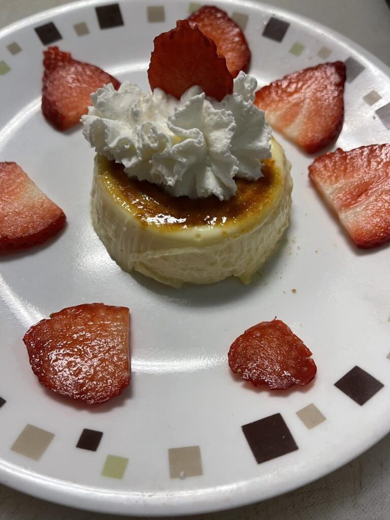 Crème caramel with whipped cream and fresh strawberries