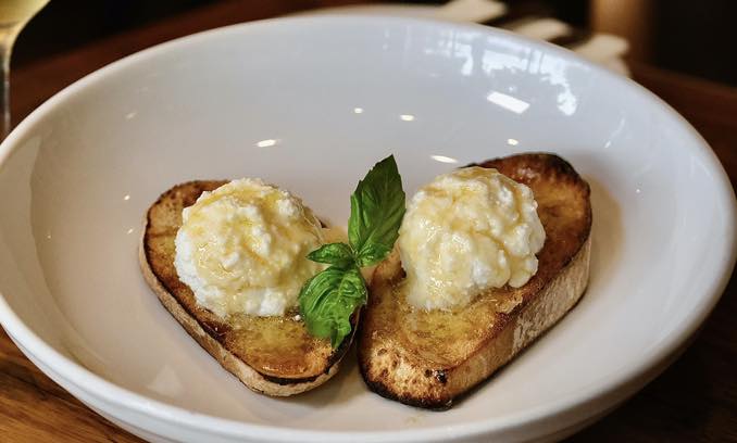 Whipped ricotta crostini drizzled with honey and fresh basil